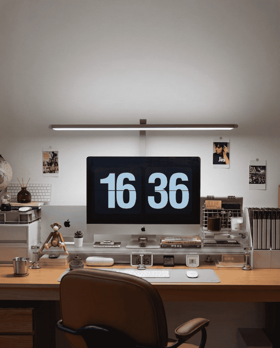 HushLume chrome plated carbon steel and acrylic desk shelf organizer under an iMac and monitor desk lamp in a cozy workspace setup.