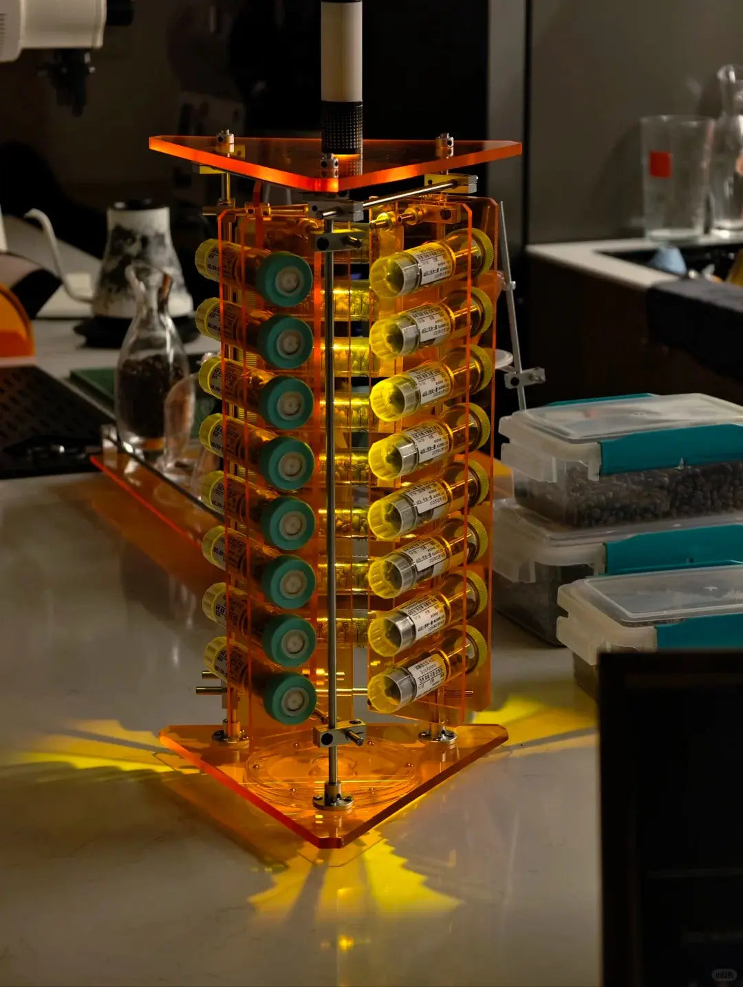 HushLume Pro coffee bean display stand with amber orange acrylic glowing under warm light, chrome steel shafts