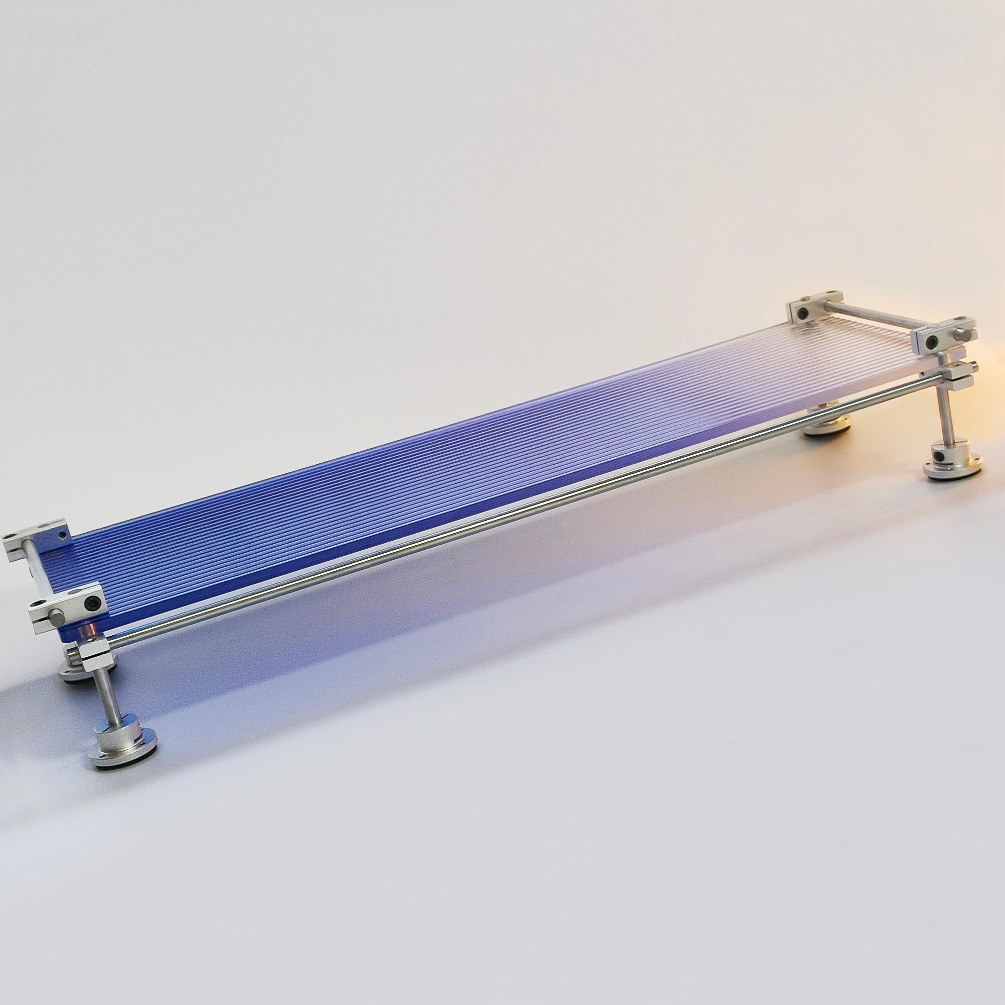 HushLume custom chrome plated steel linear shaft desk shelf with gradient blue acrylic monitor stand riser, studio product shot on white background.