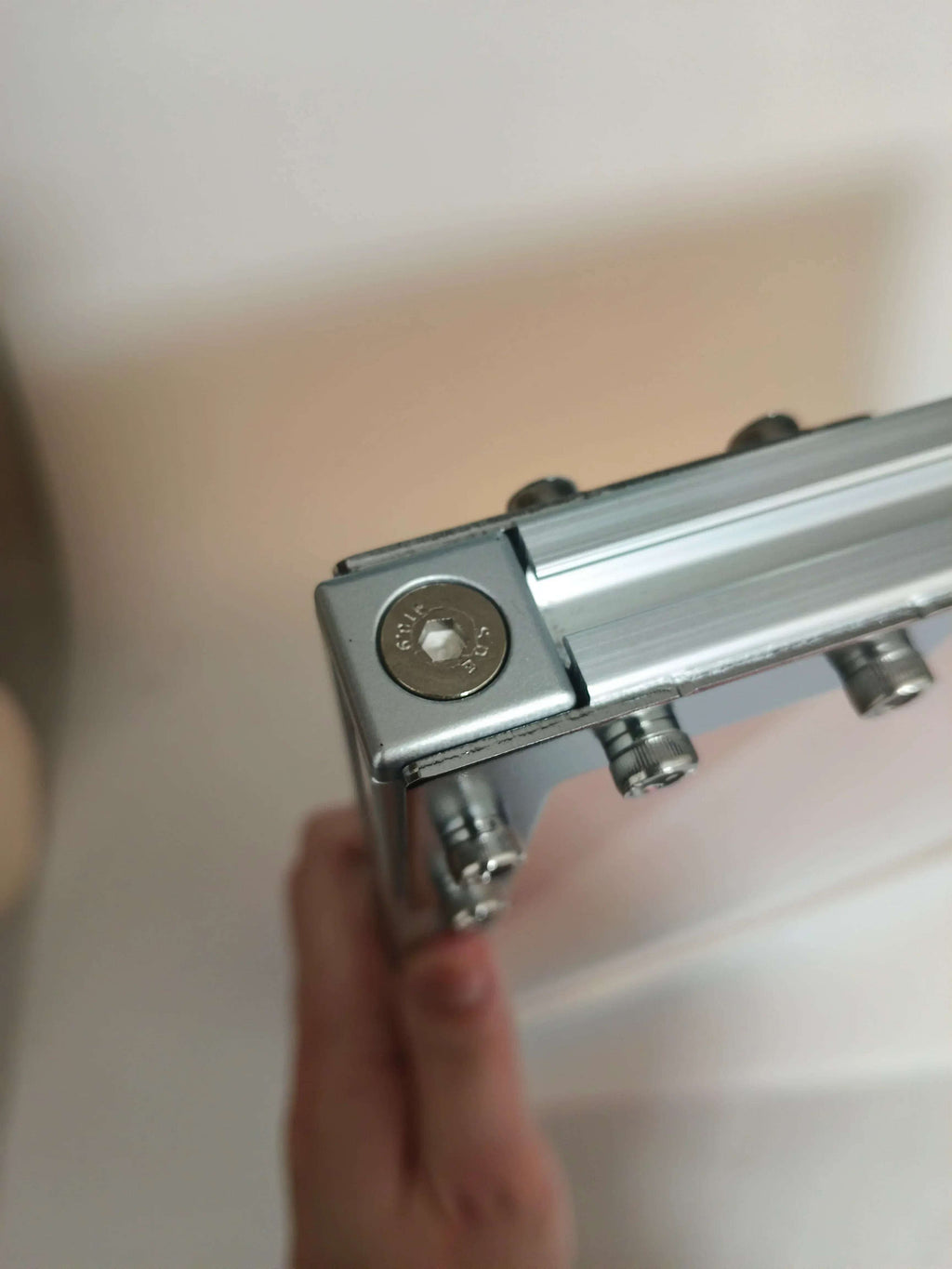 Close-up view of the corner joint mechanism on HushLume industrial aluminum frame, showing premium hex socket screws and precision engineering details.